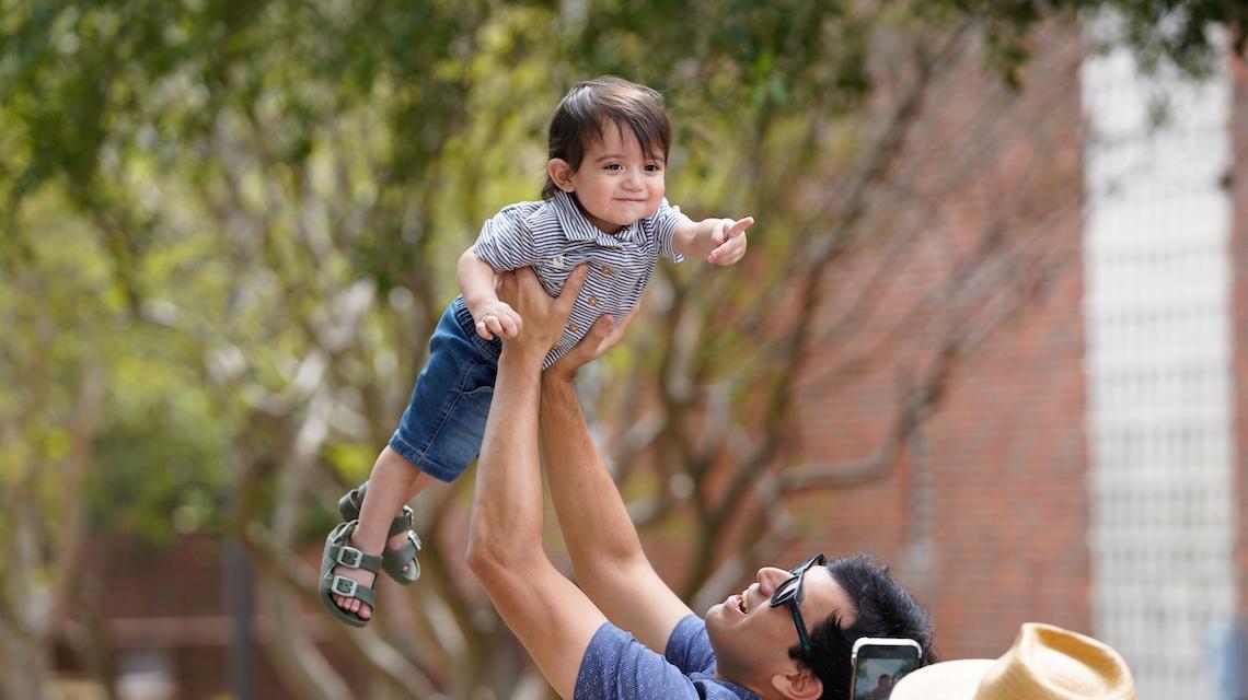 Parent holds his child in the air at 同学会 event